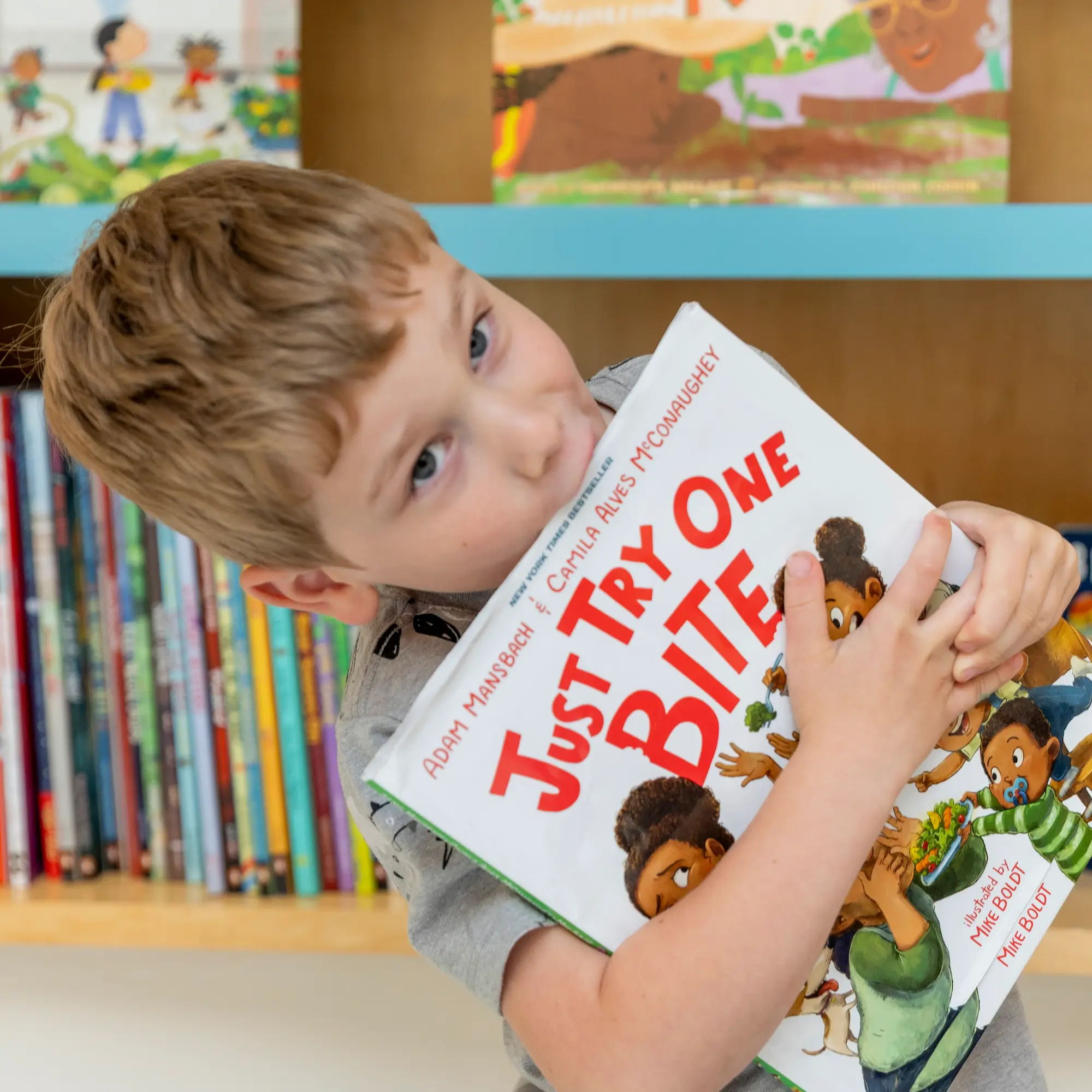 A child biting a book titled Just Try One BITE