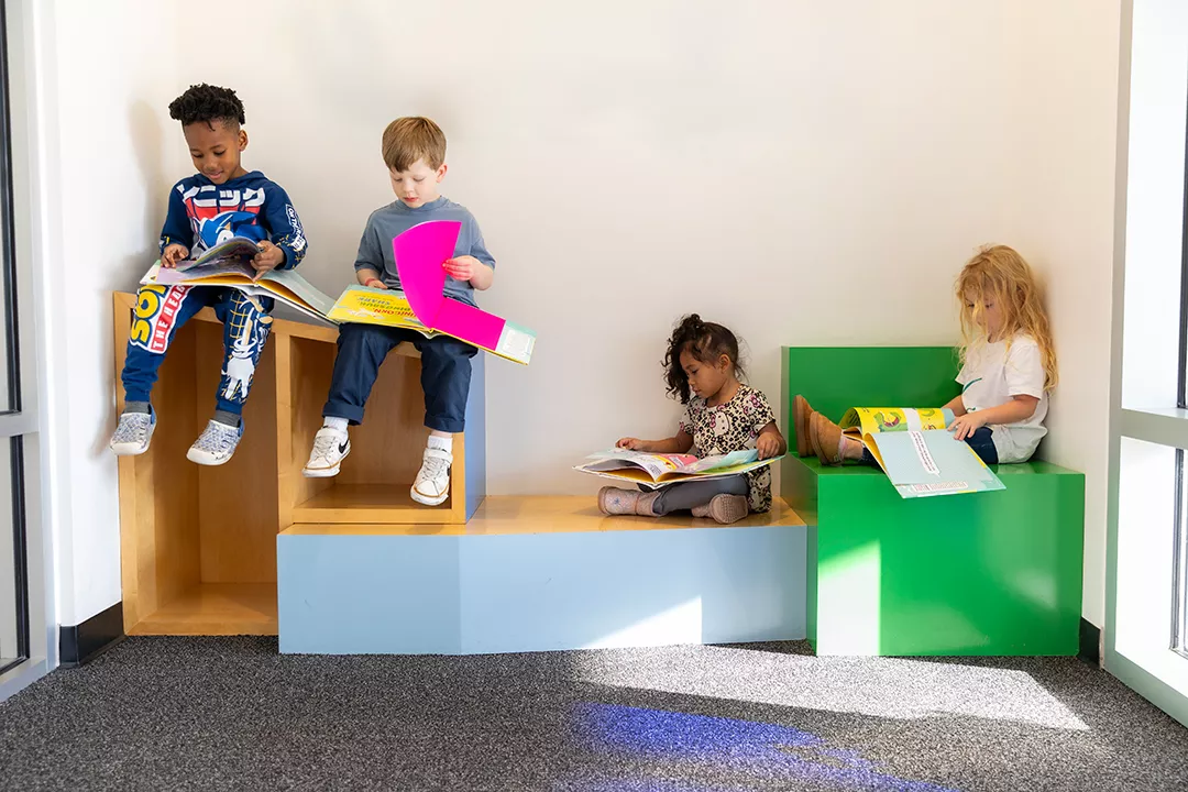 Young students at the New E3 School holding up books while reading